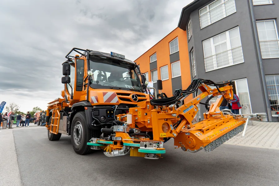 Unimog s čelním mulčovacím ramenem Mulag a rotačními kartáči na přední hydraulice