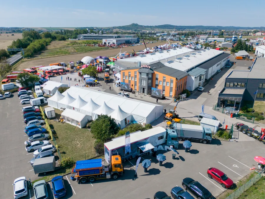 Velkokapacitní bílý stan u budovy KOBIT, před ním kamiony a oranžový vůz s nástavbou