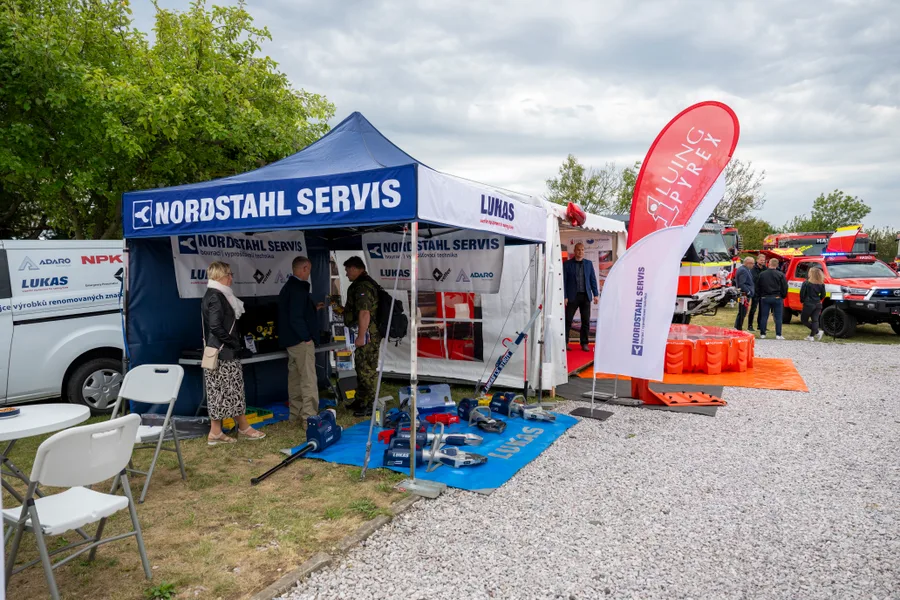 Stánek Nordstahl Servis s hydraulickými vyprošťovacími nástroji rozloženými na modré podložce, vzadu hasičská vozidla