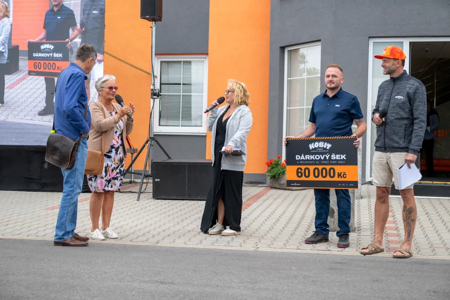Předání velkého dárkového šeku před vstupem do budovy areálu